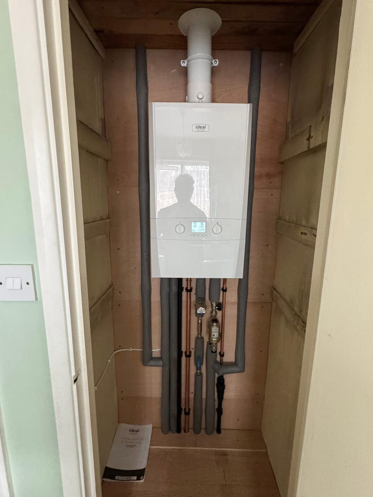 Ideal combi boiler installed in a cupboard with insulated pipework